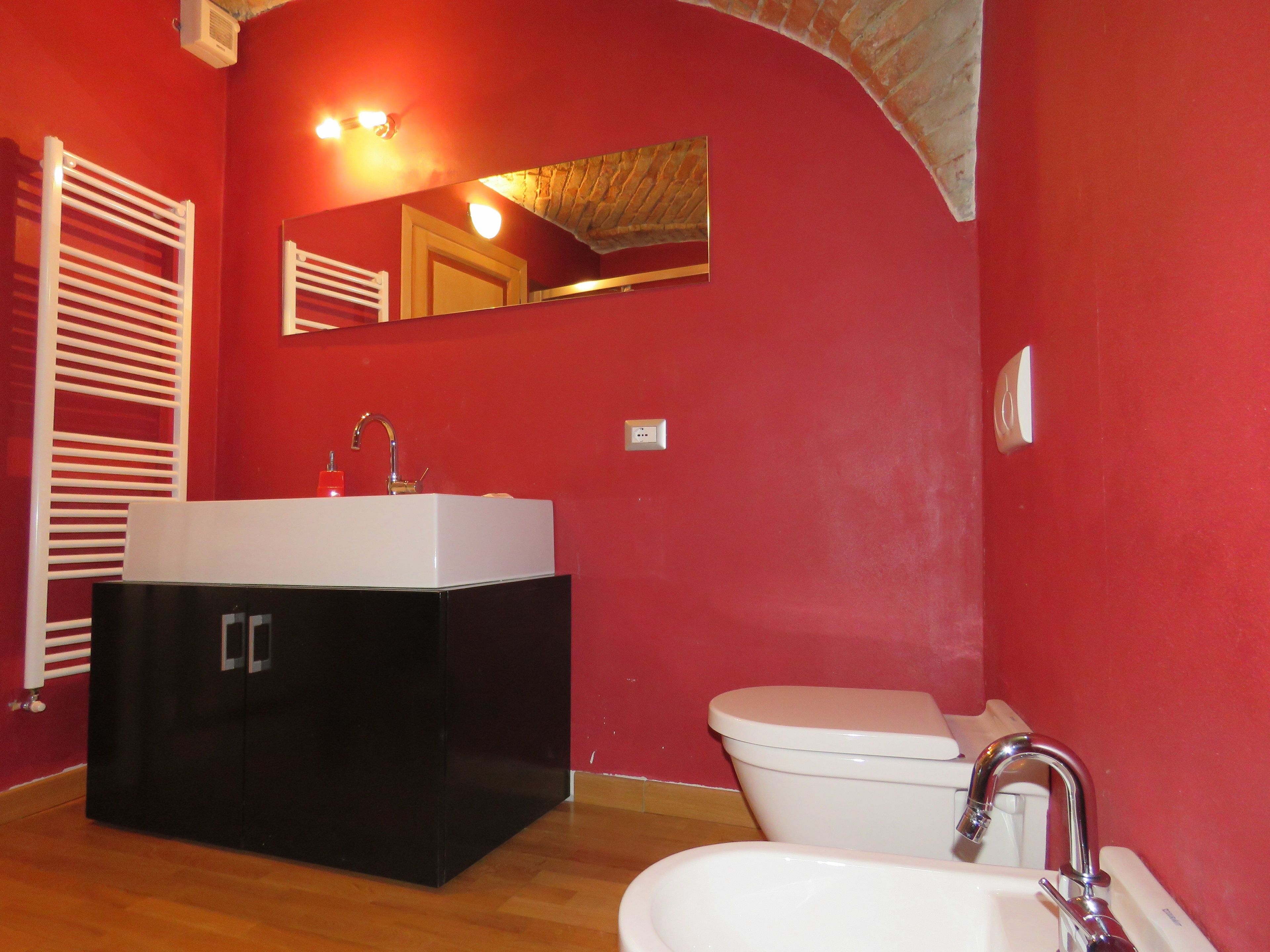 A bathroom with a black vanity, white sink, and a white toilet.