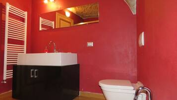 A bathroom with a black vanity, white sink, and a white toilet.
