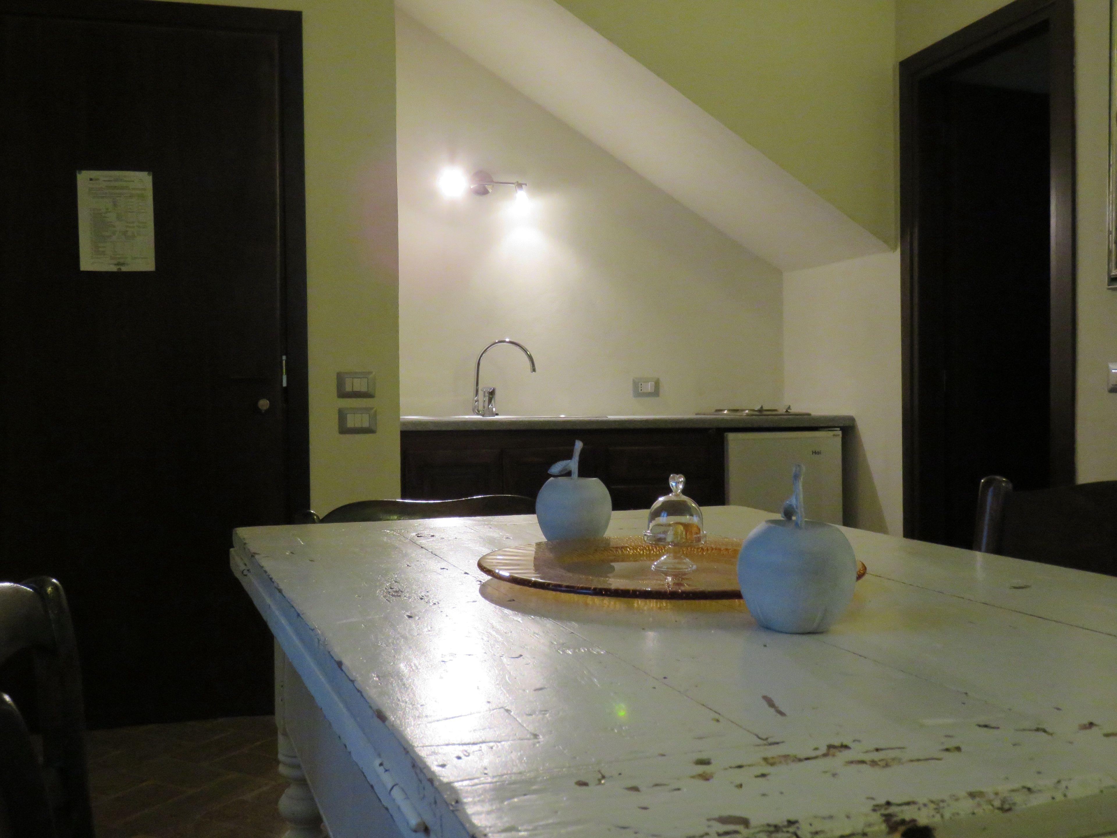 Una mesa de comedor con mantel blanco, dos adornos azules y una estructura de vidrio como centro de mesa.