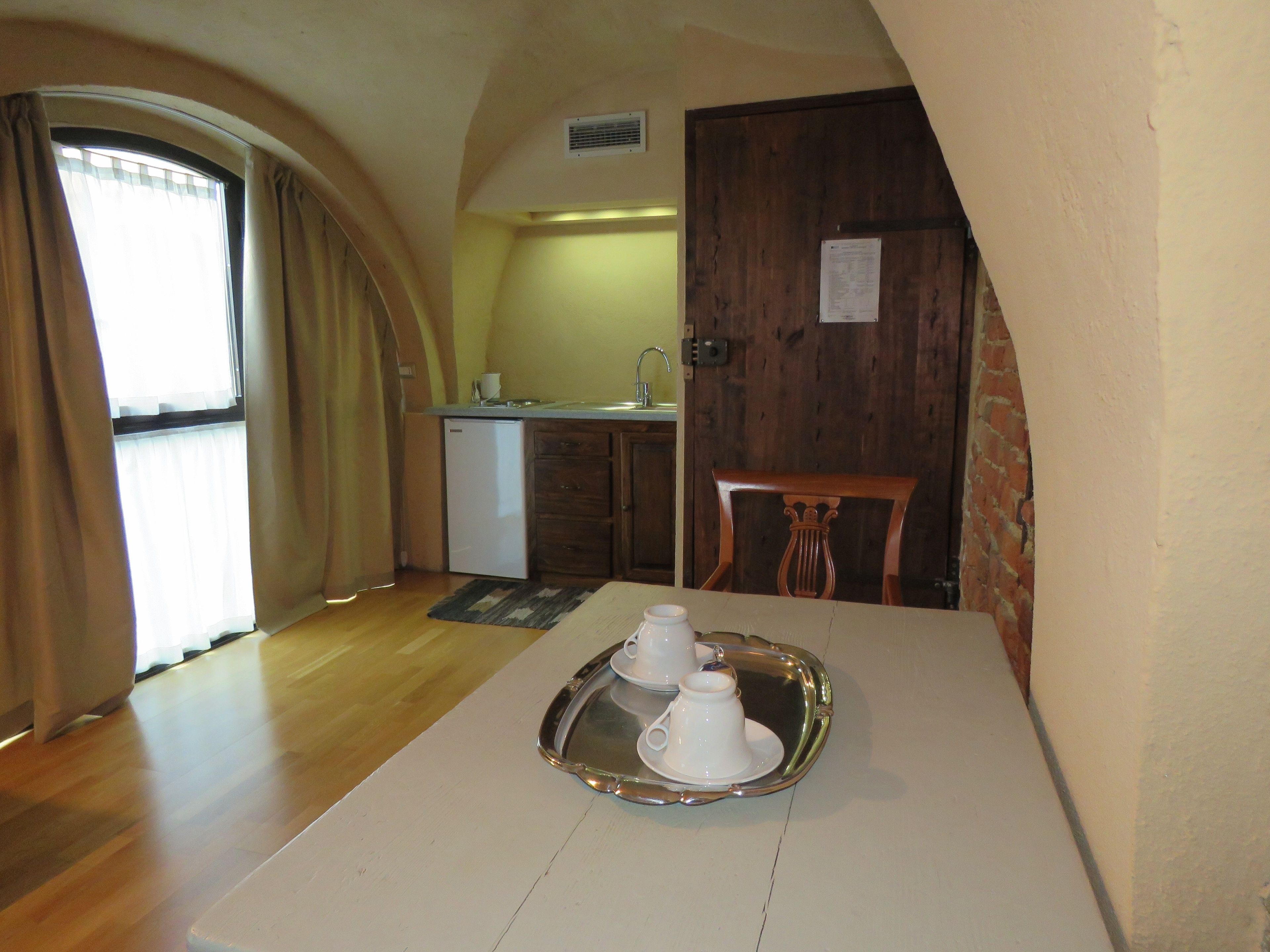 A dining area with a table set for two, a small kitchenette, and a wooden chair.