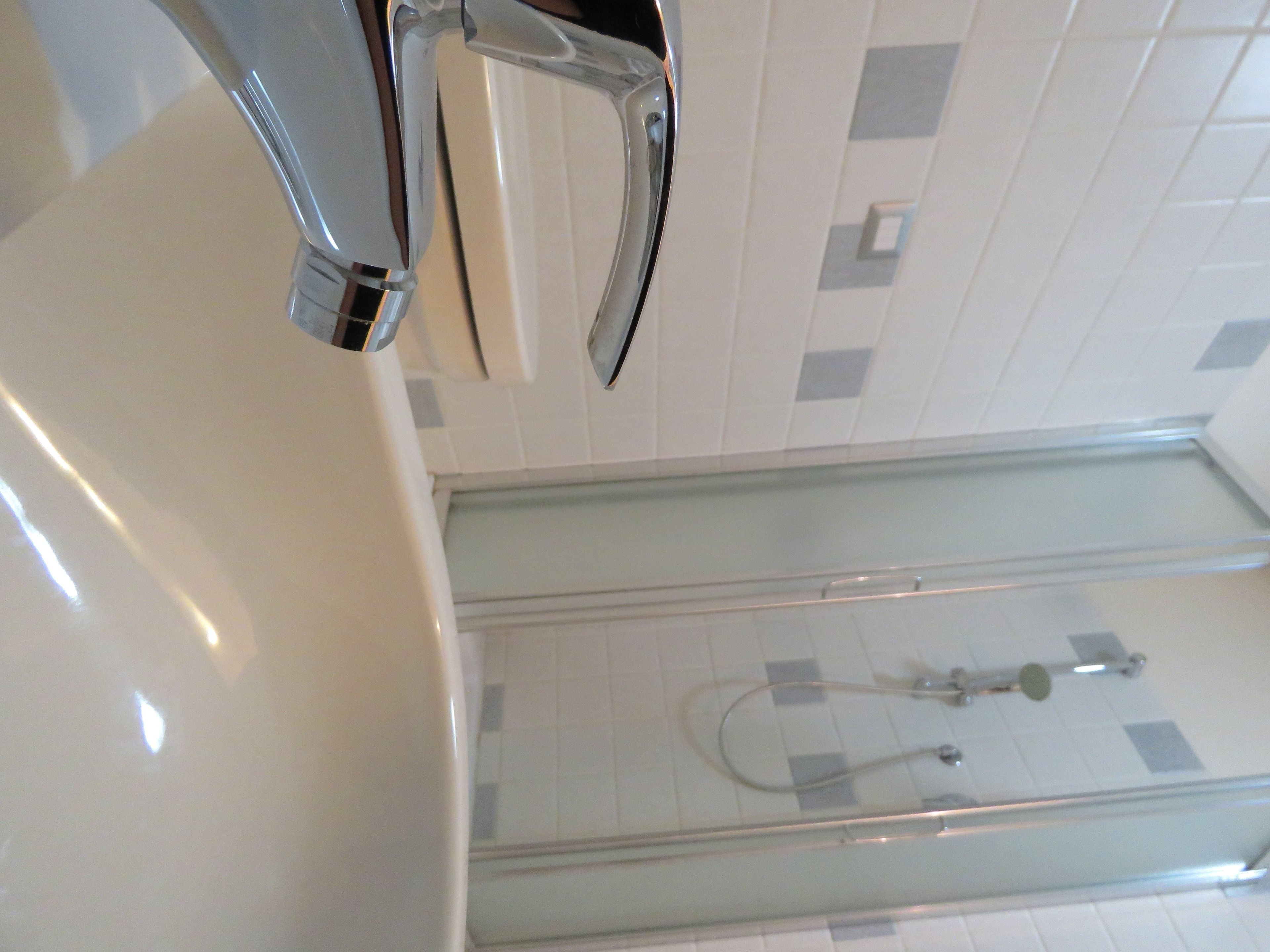 A modern bathroom with a glass shower enclosure, a chrome faucet, and tiled walls.