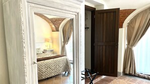 A bedroom with a bed, a nightstand, a lamp, and a window with curtains. - Relais Palazzo Paleologi - Secolo XIV (Lu e Cuccaro Monferrato)
