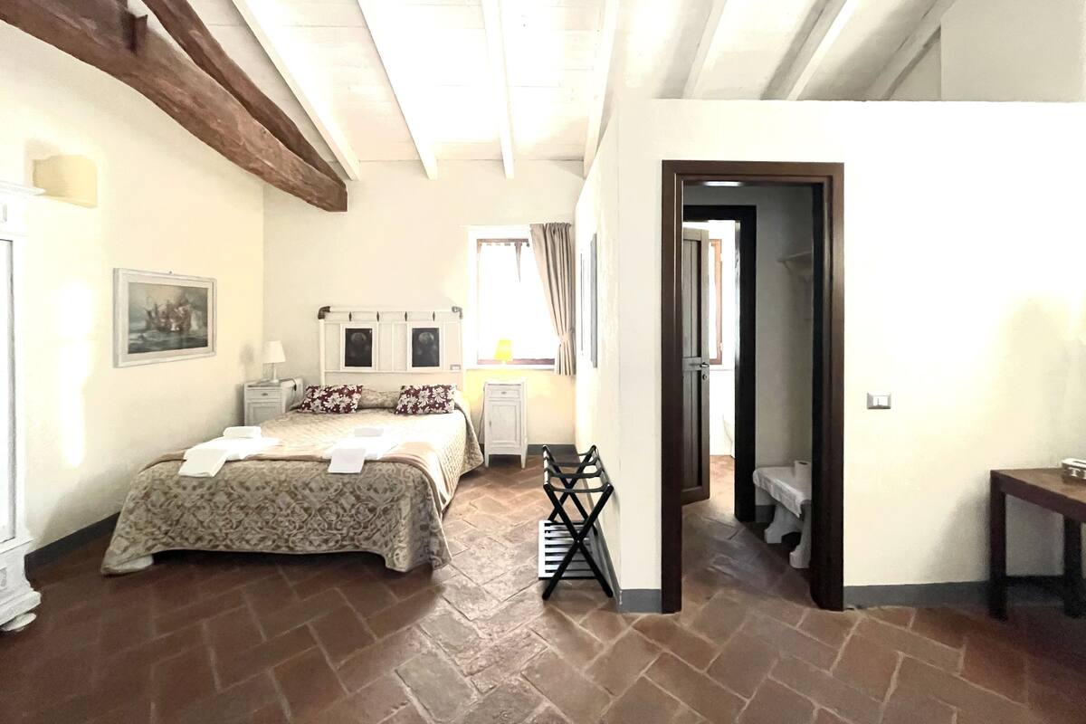 Ein Schlafzimmer mit einem Bett, einem Nachttisch, einer Lampe, einem Sessel und einer Tür zu einem anderen Raum.
