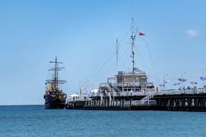 A tall ship docked at a pier with a viewing platform and a building with a sign. - Villa Sedan - Destigo Hotels (Sopot)