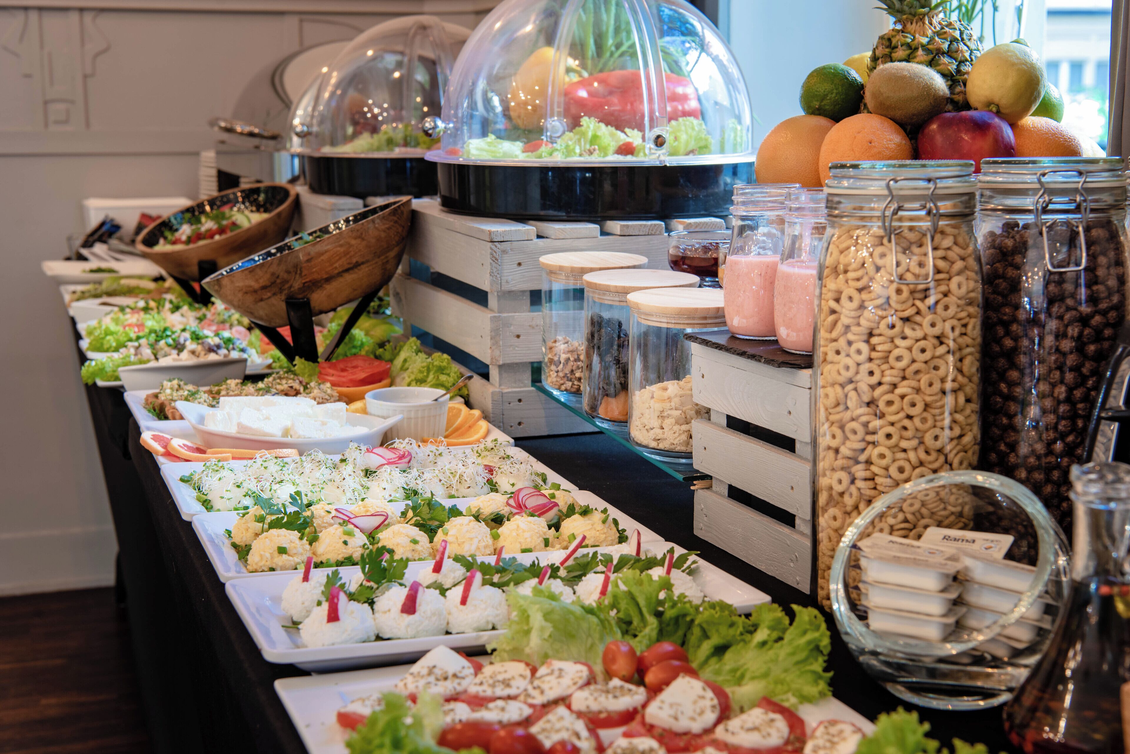 Un bufé con diversas opciones de comida, como ensaladas, frutas y cereales.
