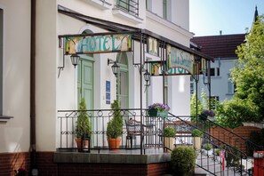 A hotel entrance with a covered porch, green doors, and potted plants. - Villa Sedan - Destigo Hotels (Sopot)