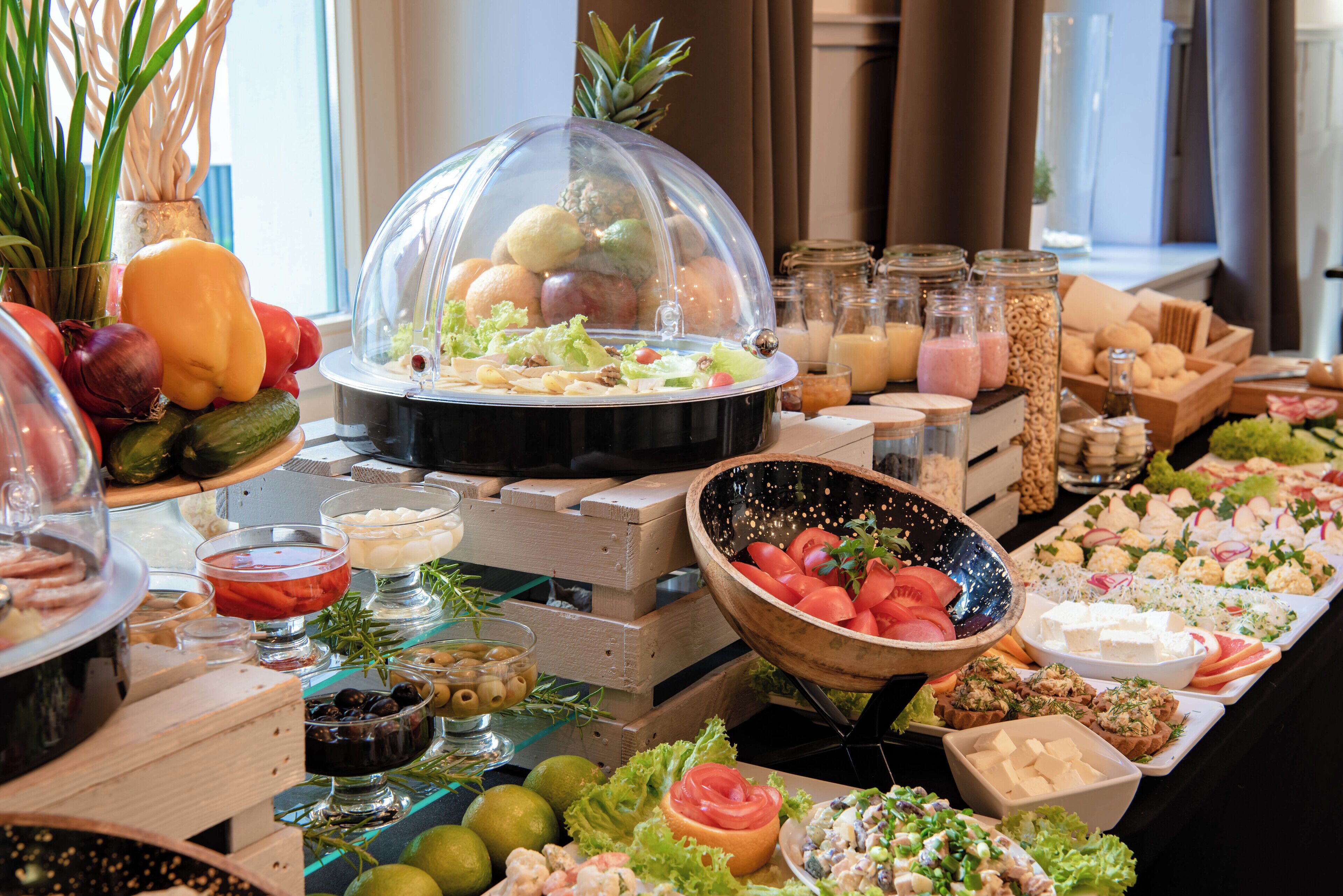 Un bufé con diferentes opciones de comida, como frutas, verduras y quesos.