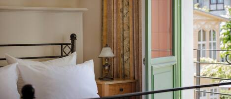 A bed with white bedding, a bedside lamp, and a window with curtains.