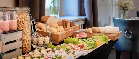 A buffet table with various food items including cereals, bread, and salads.