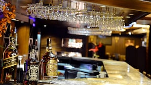 A bar area with bottles of whiskey and glasses hanging from the ceiling. - Le Cedrus Hotel (Al Arz)