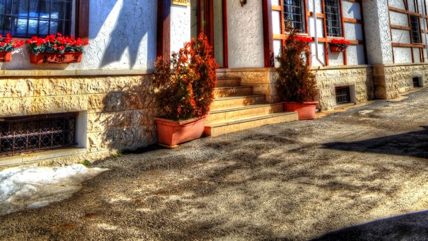 A building with a stone facade, multiple windows, and a variety of flags. - Le Cedrus Hotel (Al Arz)