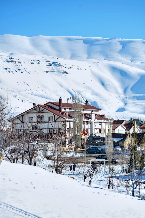A snow-covered mountain with a traditional chalet-style building in the foreground.