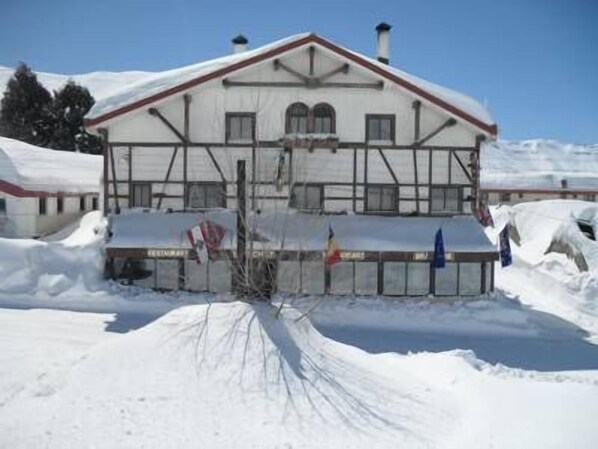 Un edificio cubierto de nieve con un estilo arquitectónico tradicional, que presenta un tejado a dos aguas y varias ventanas.