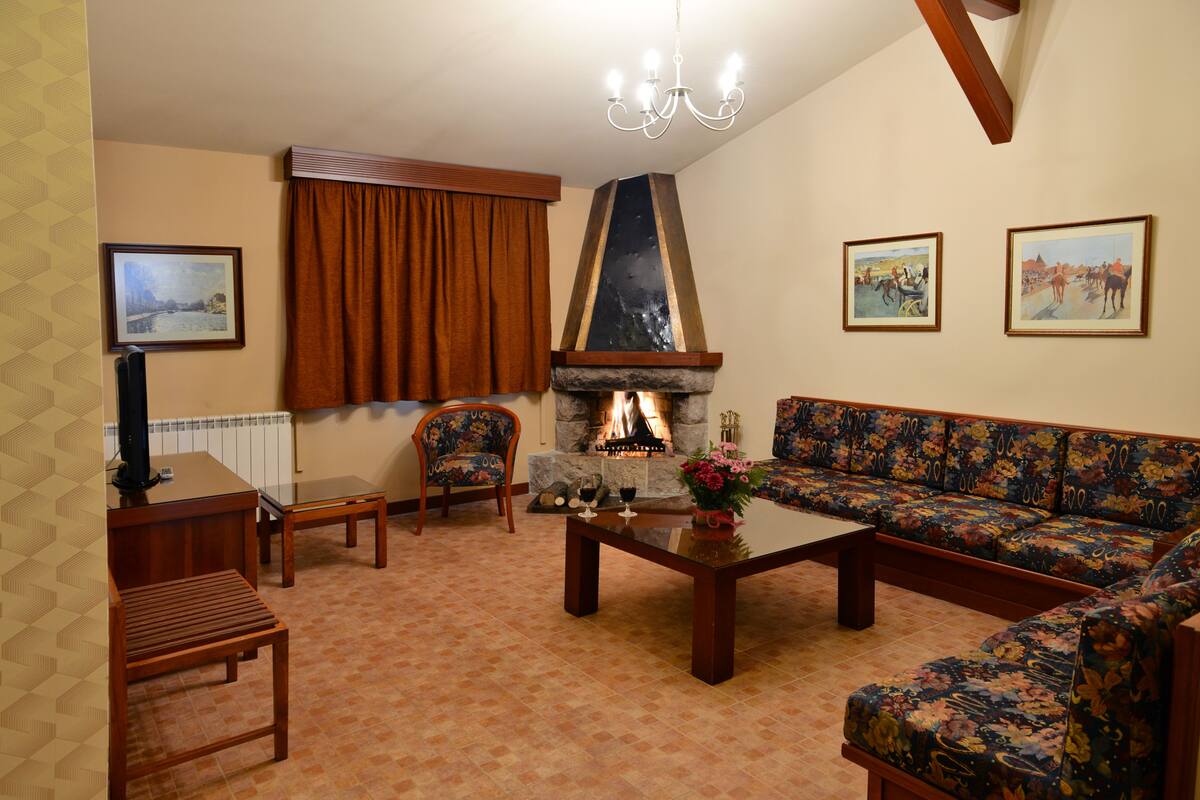 A living room with a fireplace, a sofa, a chair, a coffee table, and a television.