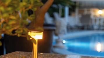 A table with a lamp, a pool, and a plant in the background.