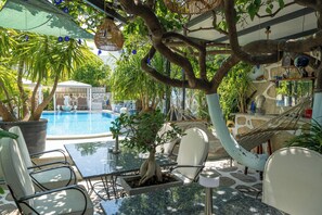 Un área junto a la piscina con una mesa de vidrio, sillas y una hamaca.