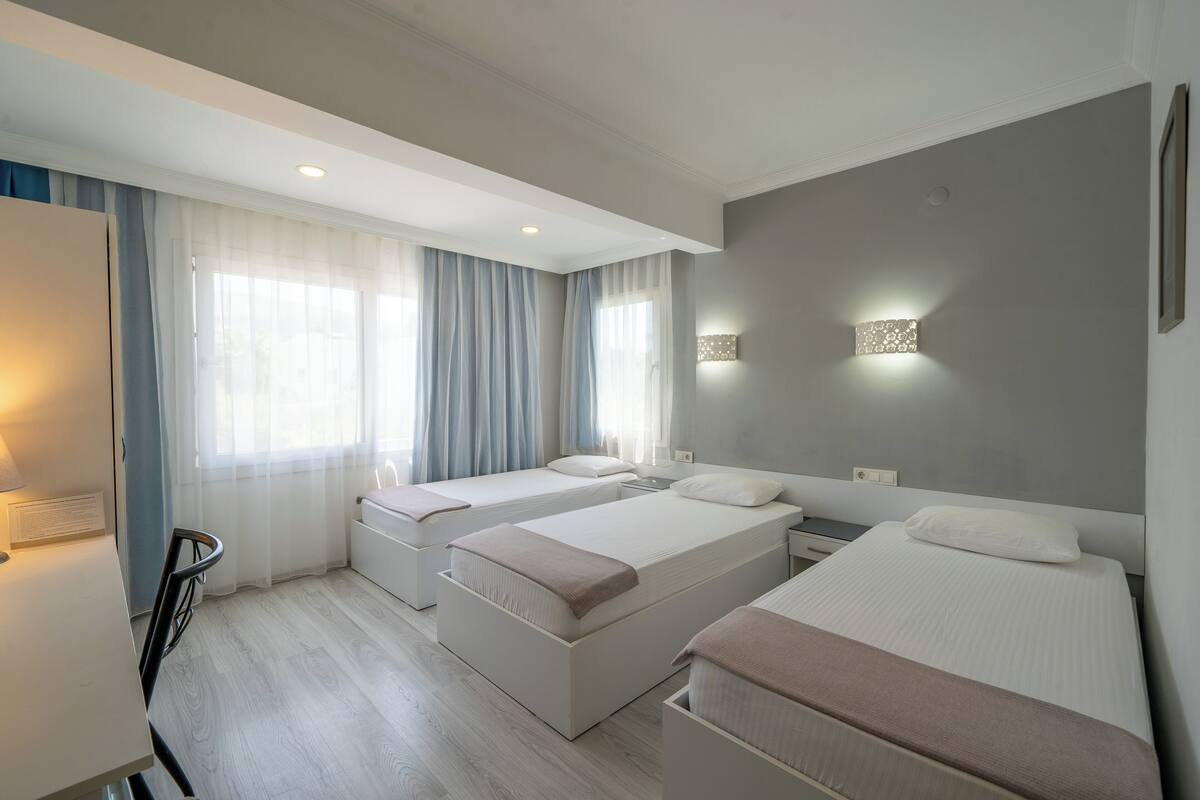 Habitación de hotel con tres camas, un escritorio y una silla.