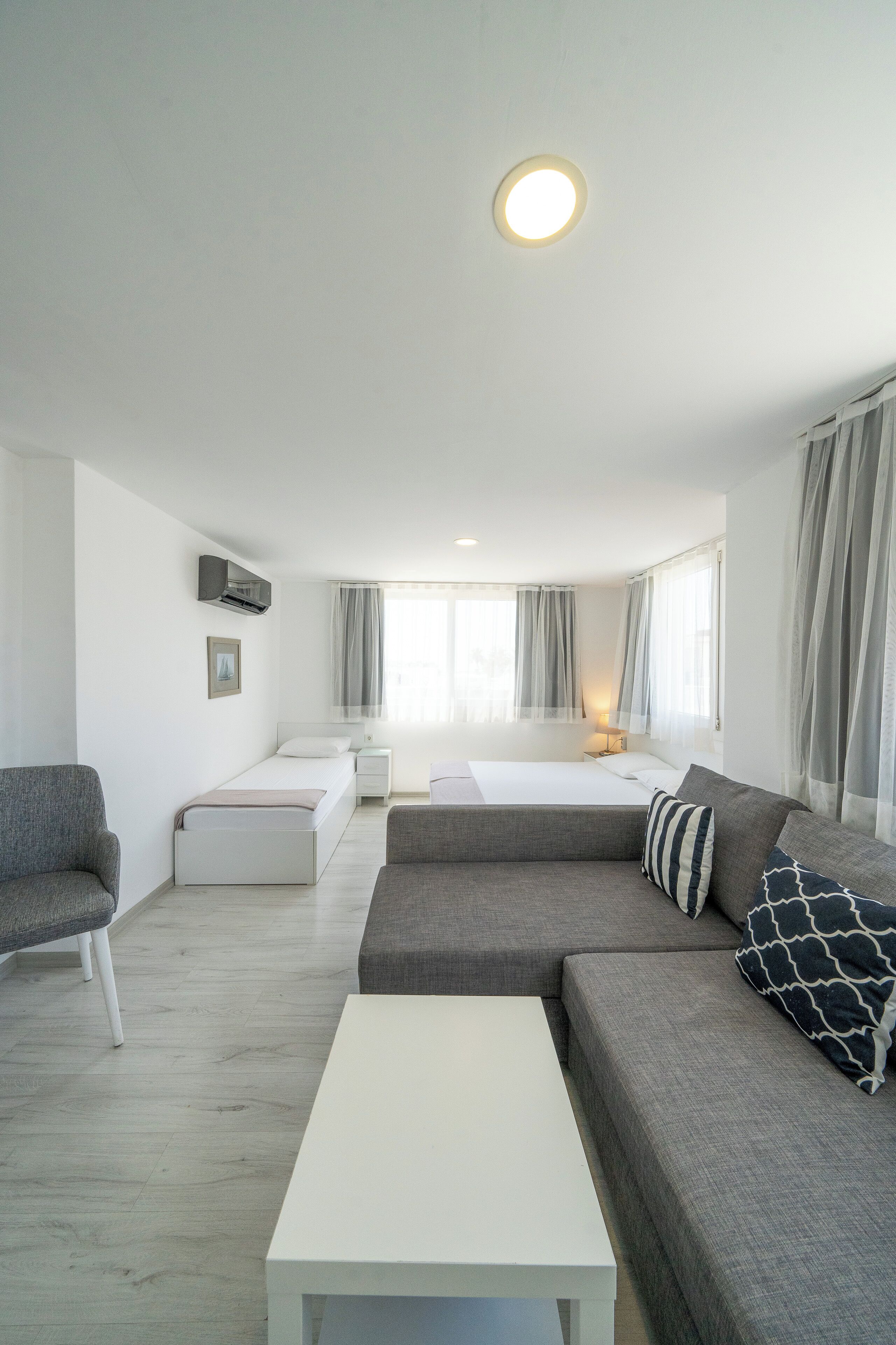 A modern hotel room with a large bed, a sofa, a small table, and a chair.