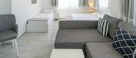 A modern hotel room with a large bed, a sofa, a small table, and a chair.