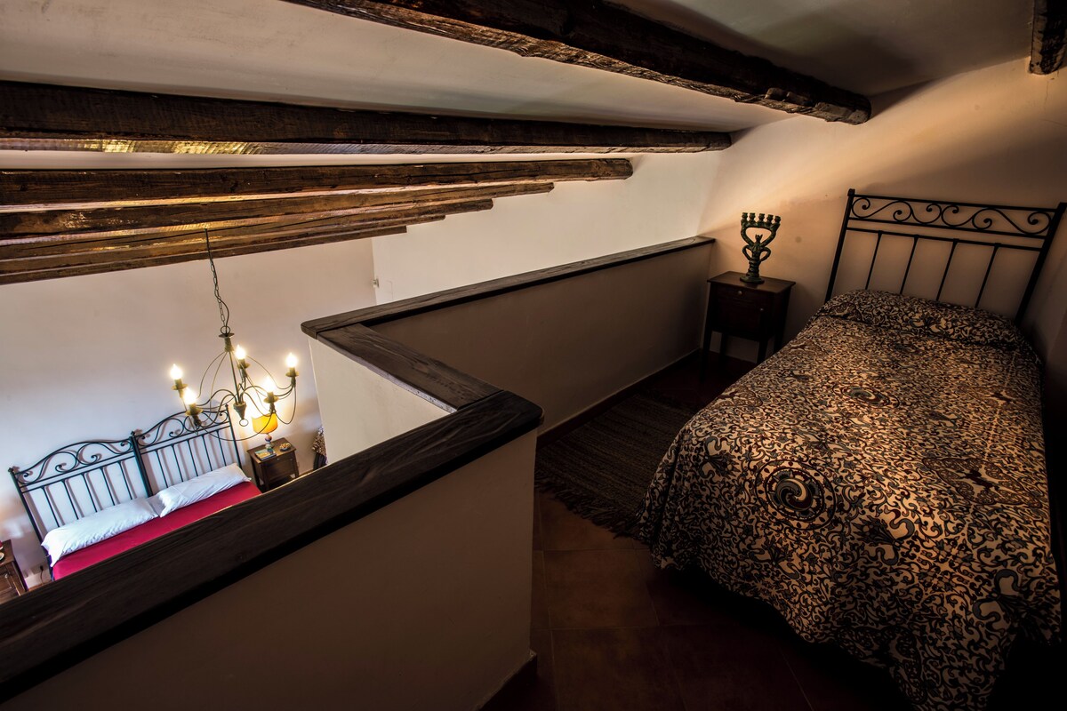 Un dormitorio con cama, mesita de noche, candelabro y vistas al piso inferior.