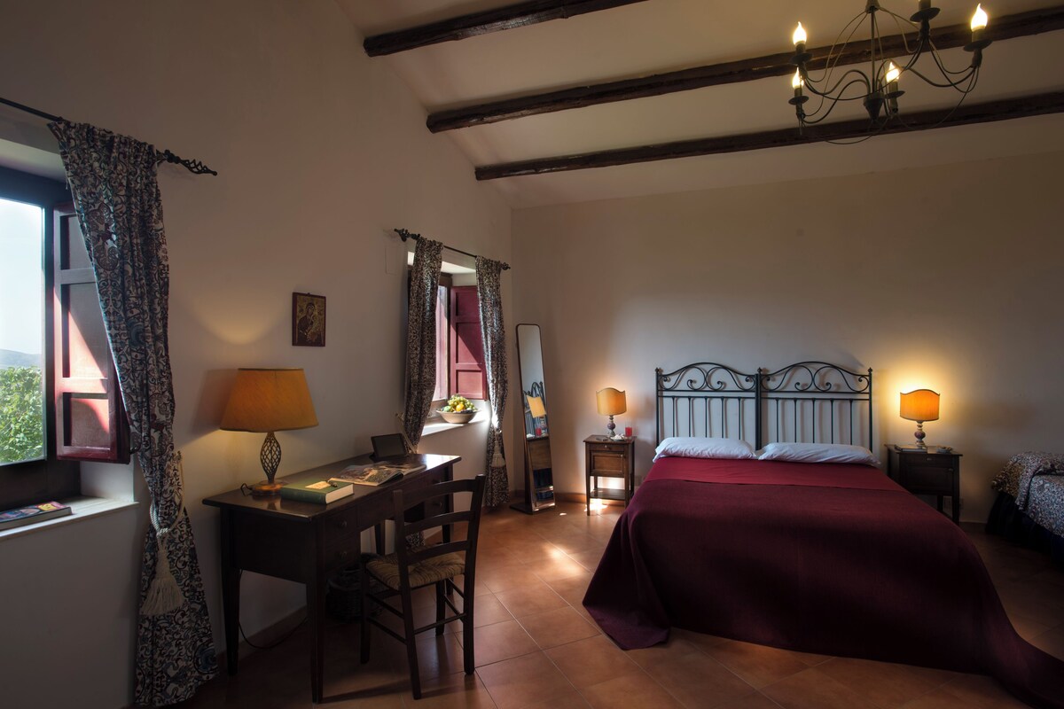 Un dormitorio con cama, escritorio, silla, lámpara y candelabro.