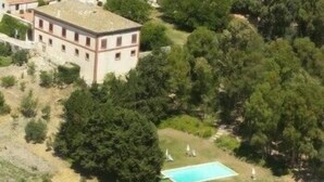 Vista aérea de un edificio rodeado de árboles frondosos y una pequeña zona con piscina.