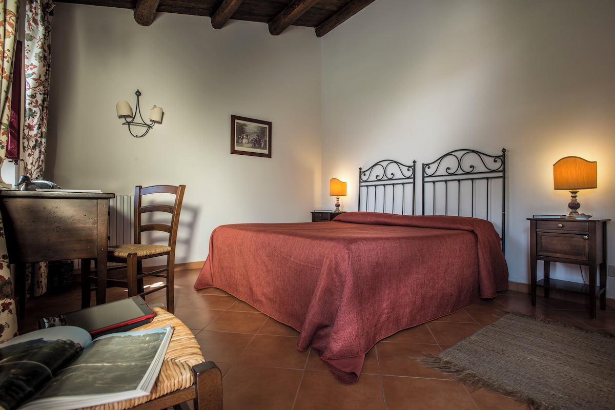 Une chambre à coucher avec un lit, un bureau, une chaise, une lampe et un tableau au mur.
