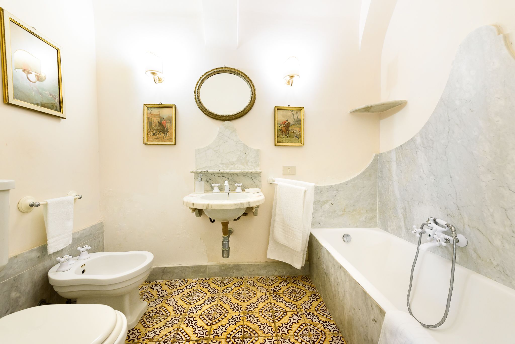 A bathroom with a bidet, toilet, sink, and bathtub.