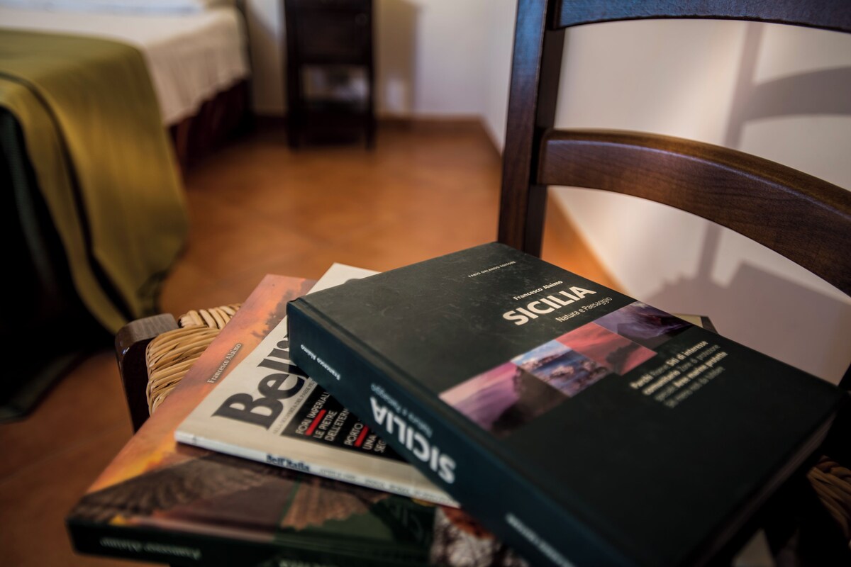 Une chaise sur laquelle se trouve un livre intitulé « Sicilia » ainsi que d’autres livres.