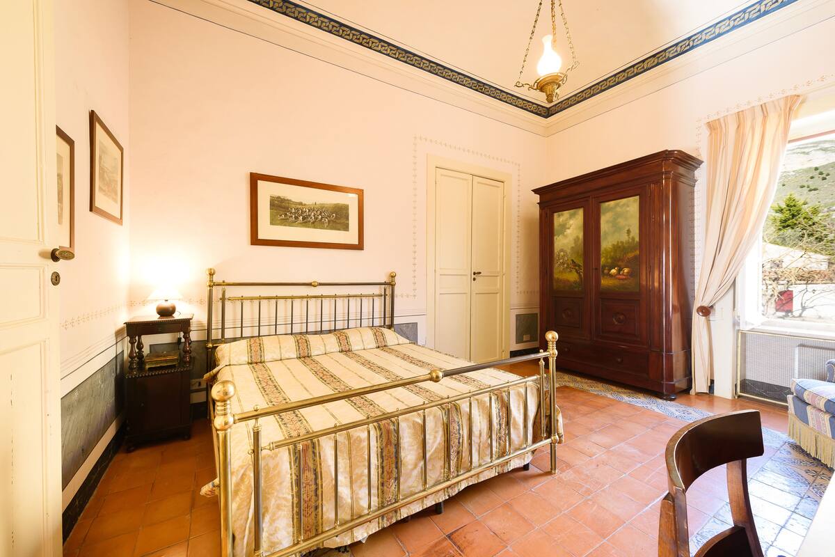 Un dormitorio con cama, un armario de madera, una silla y un cuadro en la pared.