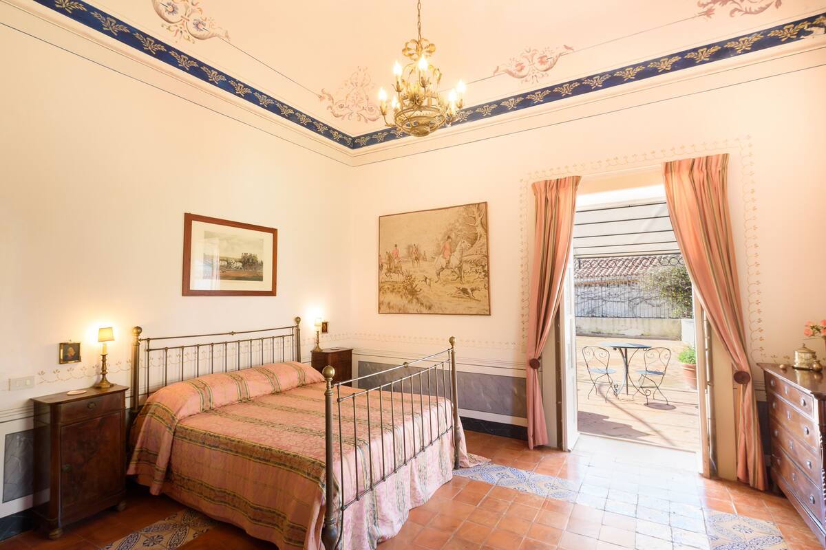 Un dormitorio con una cama, lámparas de noche, un cuadro y vistas al exterior.