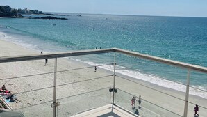 A beach view from a balcony with a glass railing, a pool, and a clear sky. - Les Sables Blancs (Concarneau)