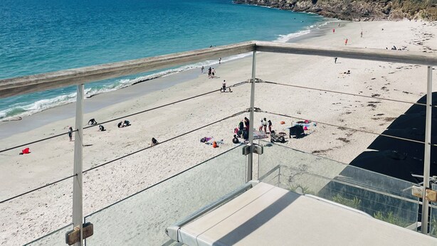 A beach with a clear view of the ocean, a sandy shore, and a metal railing. - Les Sables Blancs (Concarneau)