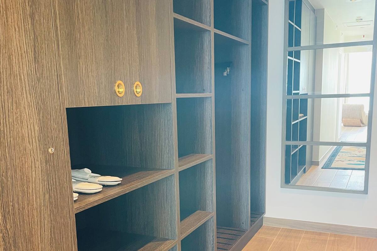 Una habitación con un amplio armario de madera, suelo de baldosas y vistas por una puerta abierta.