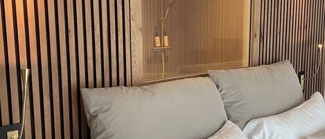 A bedroom with a wooden slat wall, a large mirror, and a bed with multiple pillows.