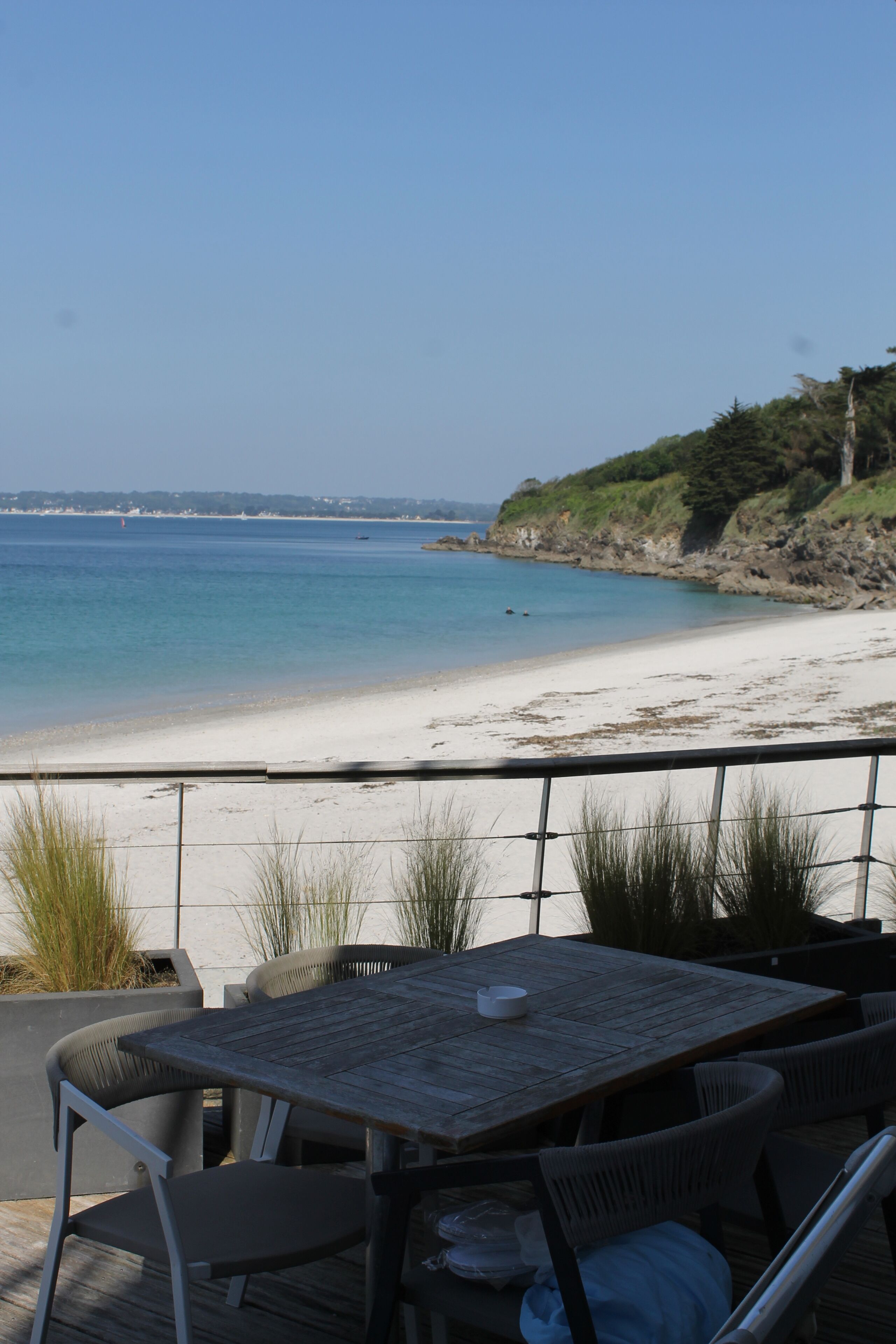 A deck with a table and chairs overlooking a beach.