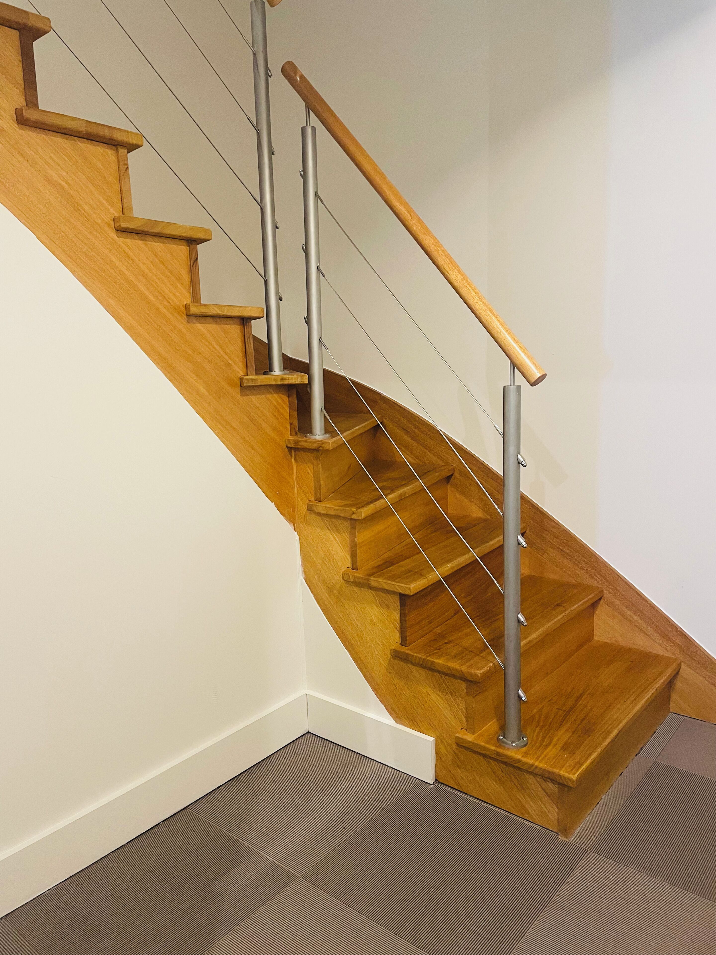 A wooden staircase with metal handrails and a carpeted floor.