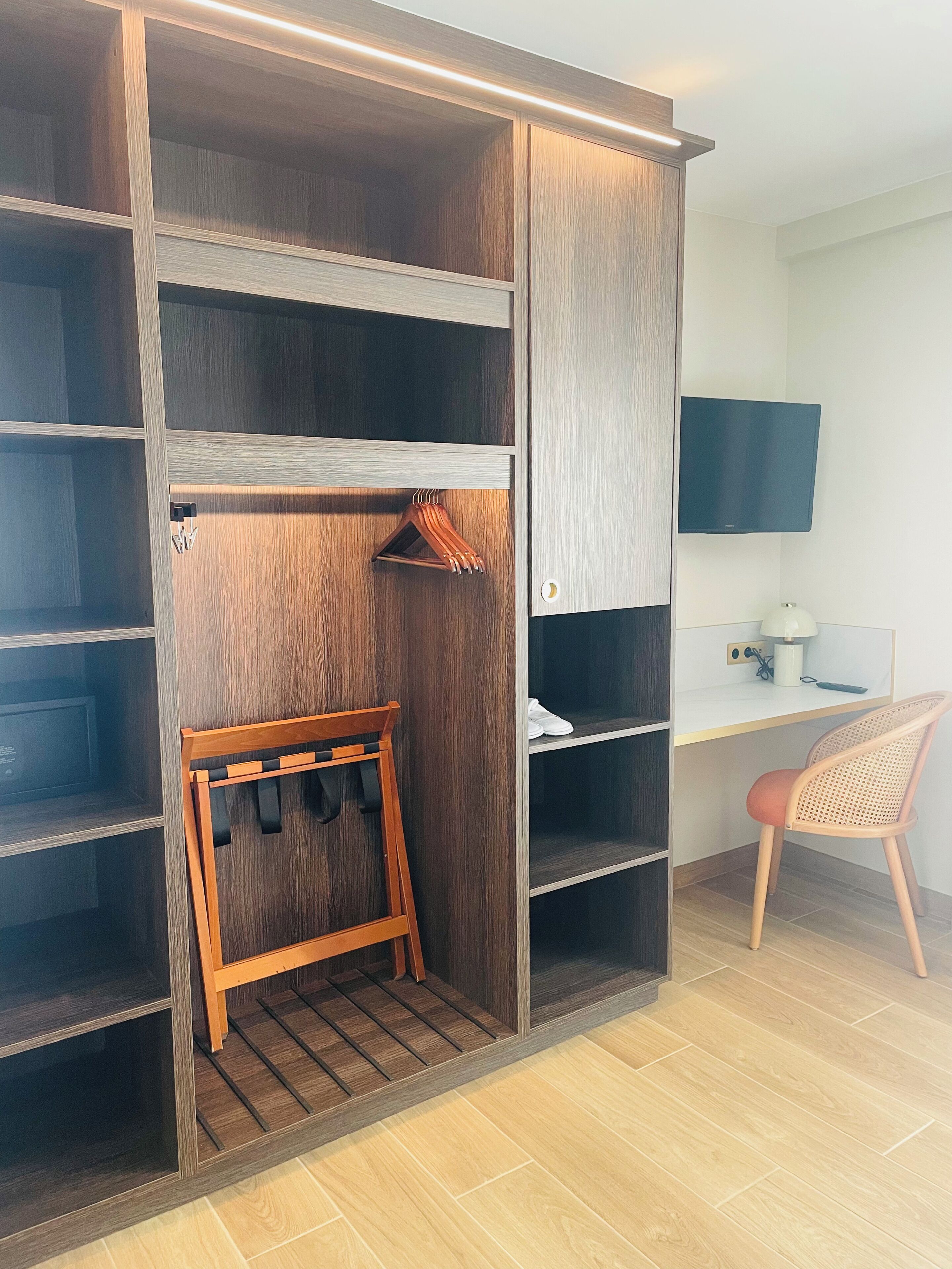 A walk-in closet with wooden shelves, a hanging rack, and a desk with a chair.