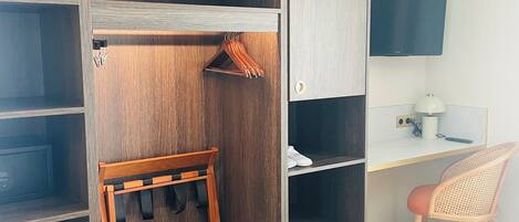 A walk-in closet with wooden shelves, a hanging rack, and a desk with a chair.