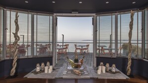 A dining area with a view of the sea, featuring a table set with candles, bottles, and jars. - Les Sables Blancs (Concarneau)