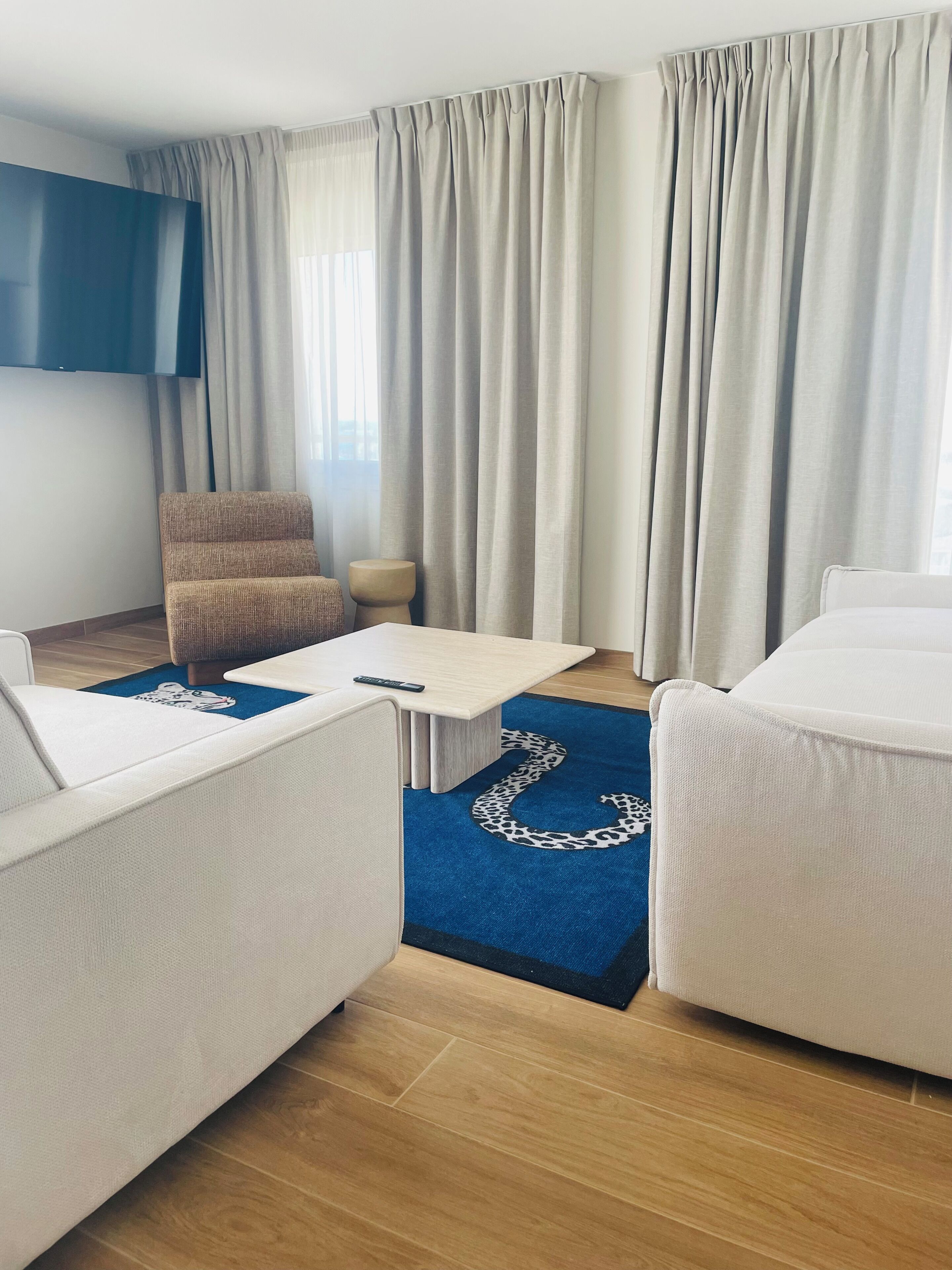 Un salon moderne avec un canapé, une table basse, un fauteuil et un téléviseur fixé au mur.