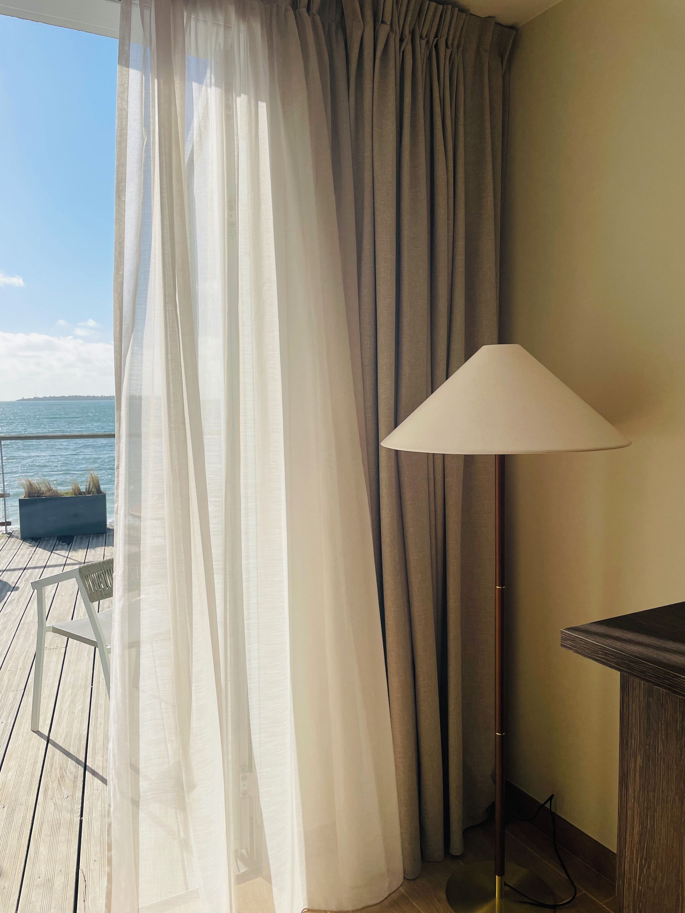 Une chambre avec vue sur la mer, une lampe et un plancher en bois.