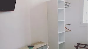 A room with a desk, chair, wardrobe, and a TV mounted on the wall. - Hôtel Danemark (Nice)