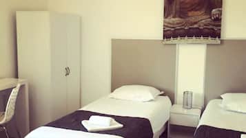 Une chambre d’hôtel avec deux lits, un bureau et un grand tableau représentant un Bouddha accroché au mur.