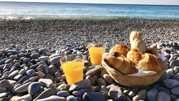 A breakfast setup on a pebble beach with croissants and orange juice. - Hôtel Danemark (Nice)