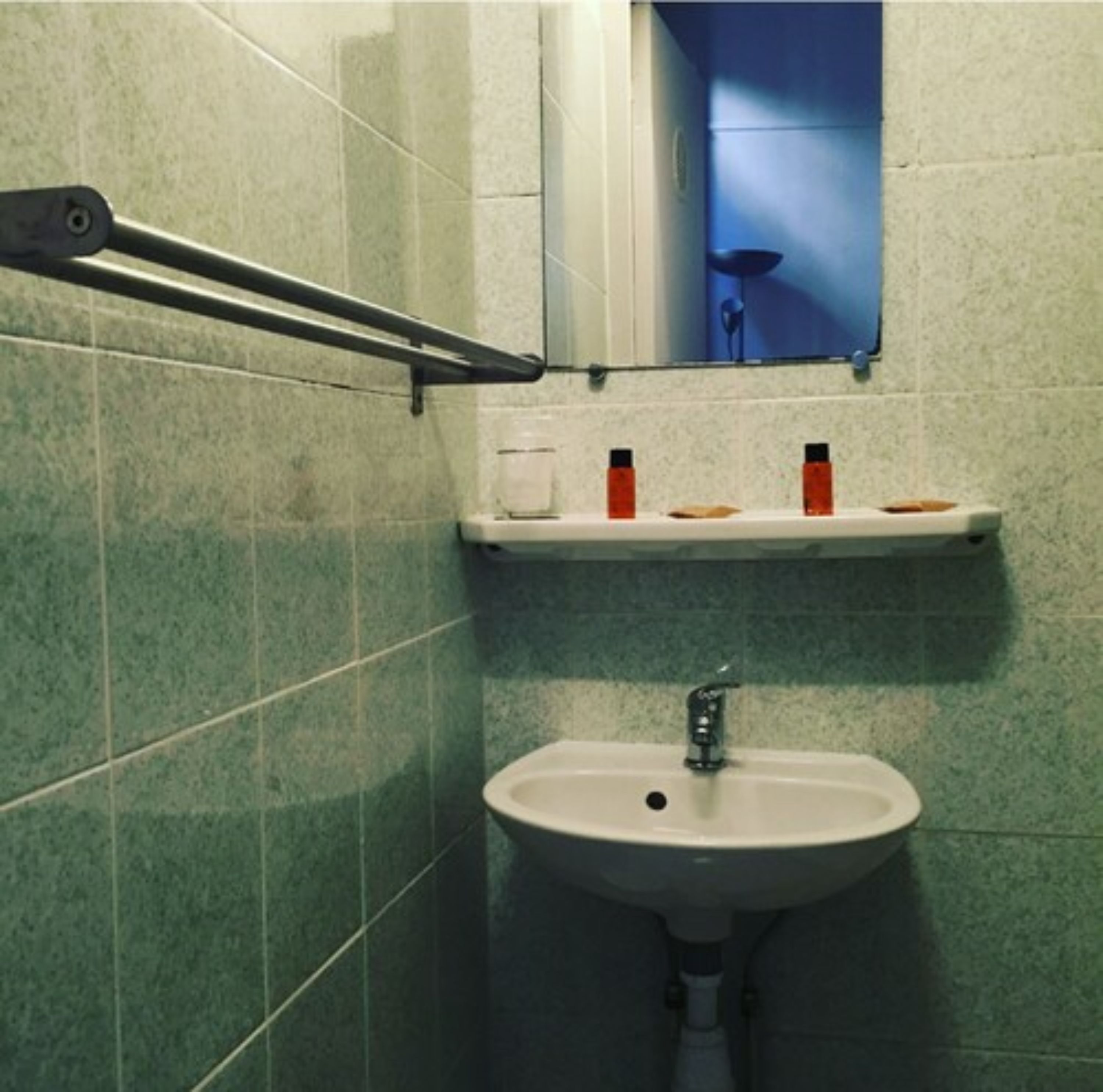 A bathroom with a sink, a mirror, and a towel rack.