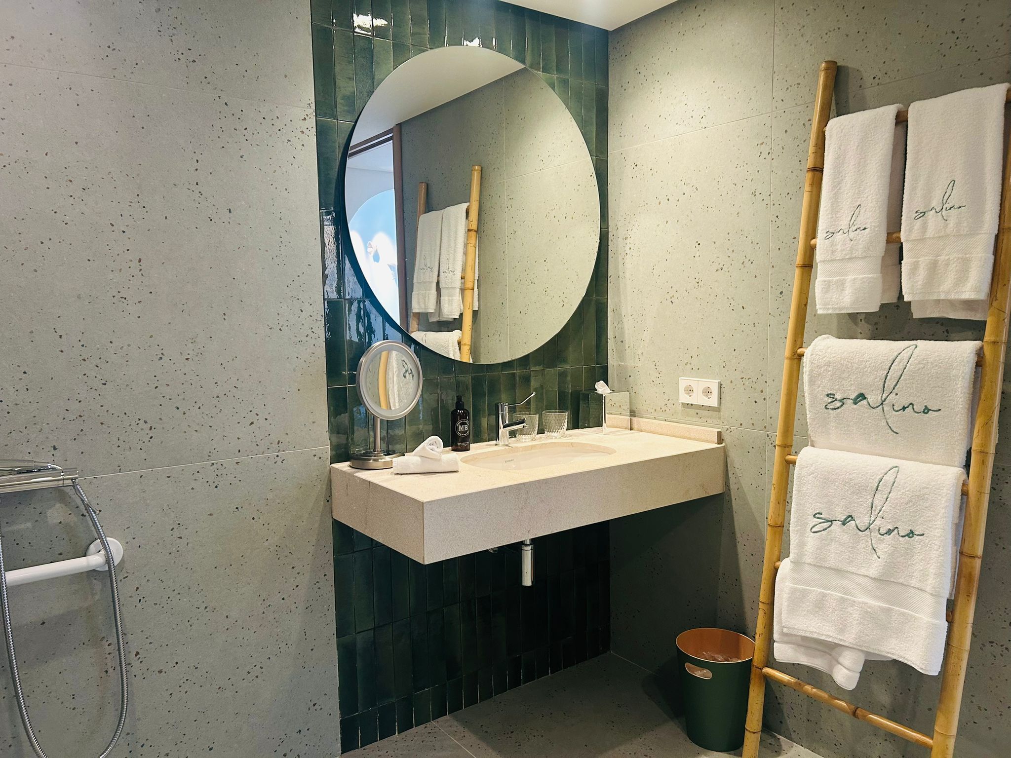 Een moderne badkamer met een vrijstaand bad, een wastafel met spiegel en een handdoekrek met handdoeken.