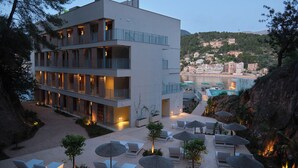 A modern hotel with multiple balconies, a pool area, and lounge chairs. - Hotel Salino Port Soller - Adults Only +16 (Sóller)