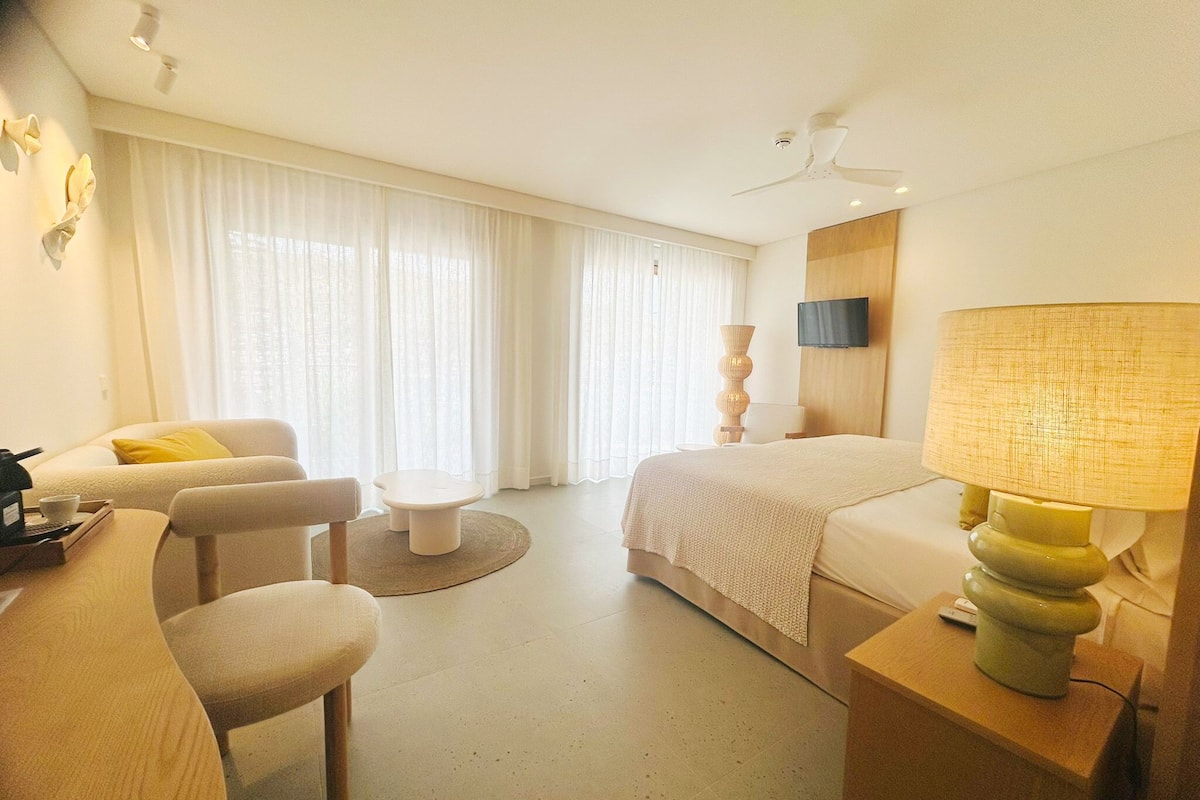 A hotel room with a bed, a desk, a chair, a TV, and a ceiling fan.