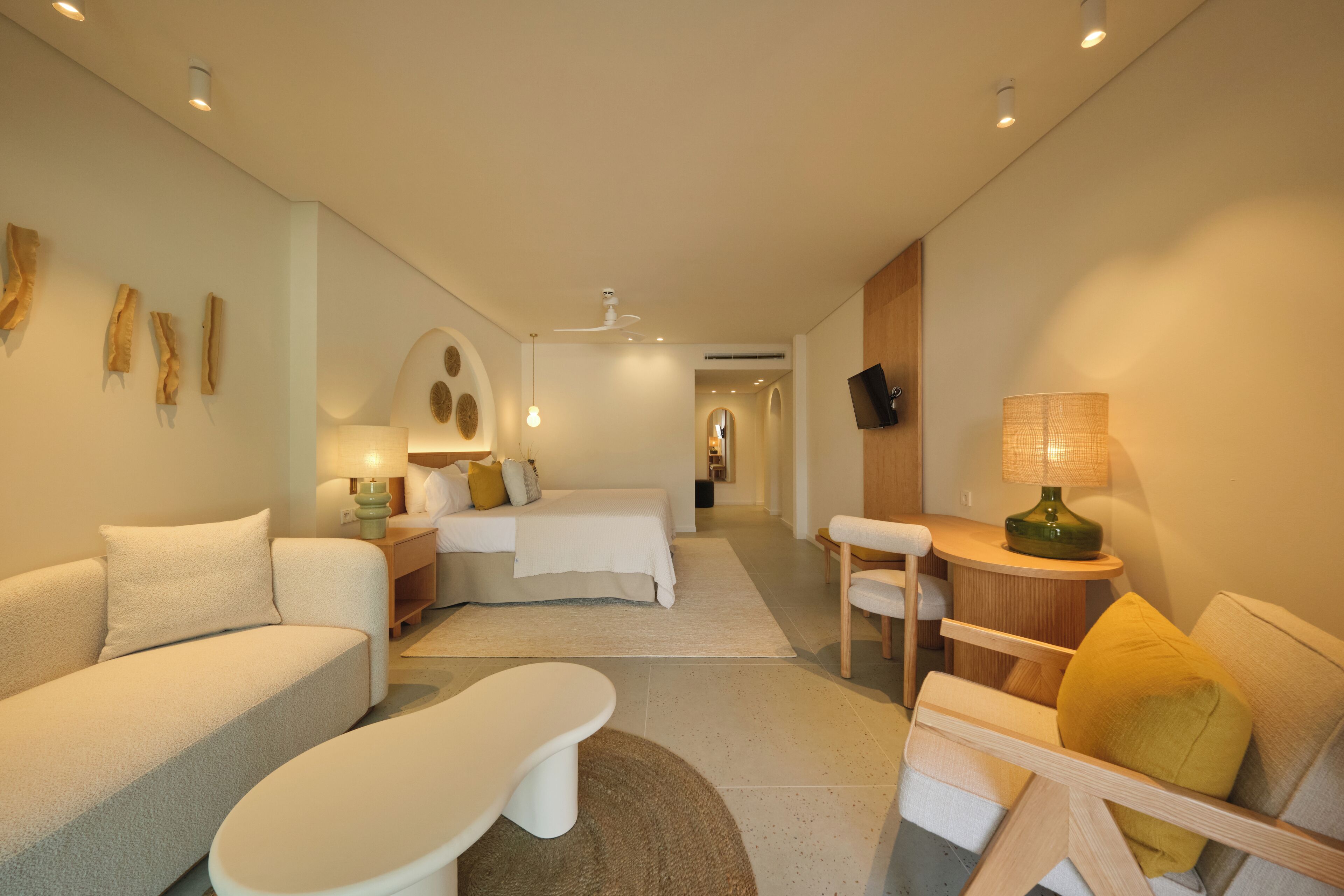 Une chambre d’hôtel moderne équipée d’un canapé, d’une petite table, d’un lit et d’un espace bureau.